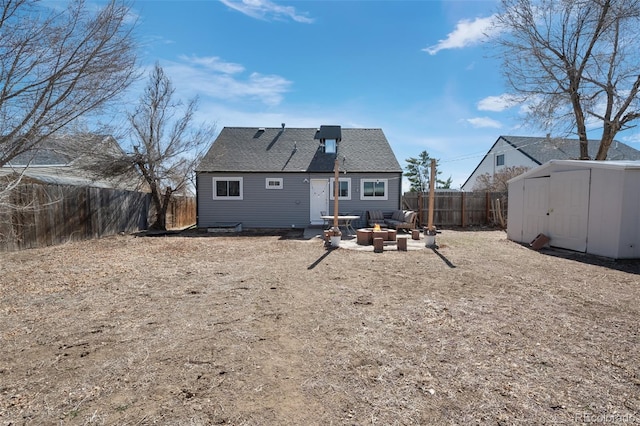 back of property featuring an outdoor fire pit, a fenced backyard, a shingled roof, an outdoor structure, and a storage shed