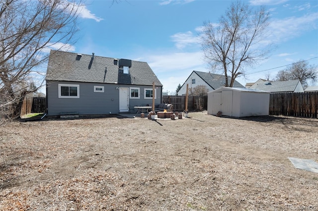 rear view of house featuring a shingled roof, a fenced backyard, an outbuilding, a storage unit, and a patio