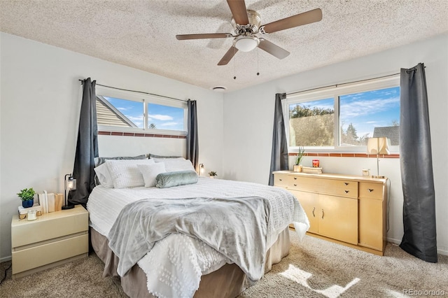 bedroom with multiple windows, a textured ceiling, light carpet, and ceiling fan