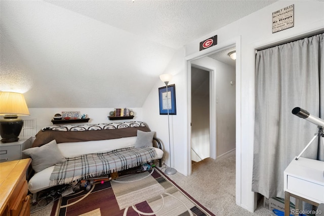 carpeted bedroom featuring a textured ceiling and vaulted ceiling