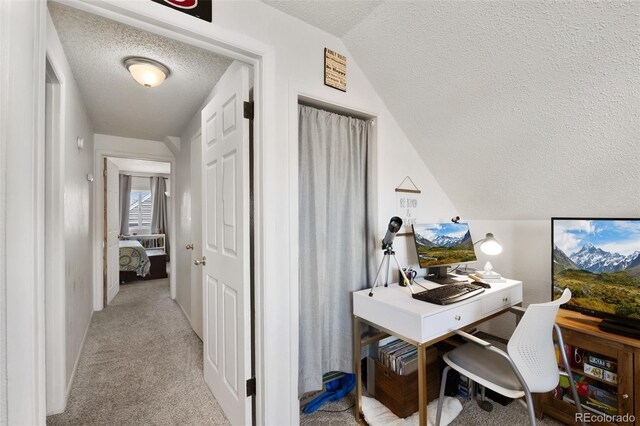 home office featuring light colored carpet, a textured ceiling, and vaulted ceiling