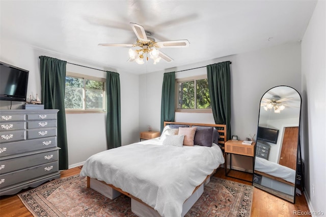 bedroom with multiple windows, wood-type flooring, and ceiling fan