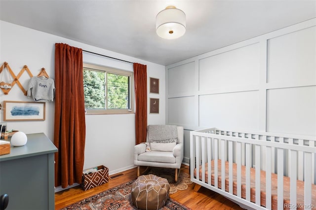 bedroom with hardwood / wood-style floors and a nursery area