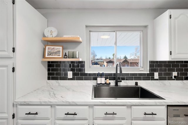 kitchen featuring tasteful backsplash, sink, light stone countertops, and white cabinets