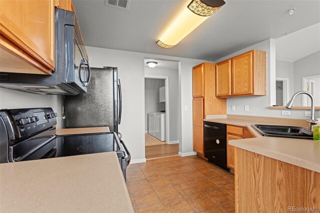 7440 S Blackhawk St Unit 207, Englewood, CO 80112 - kitchen with black appliances, washing machine and dryer, light countertops, and light tile patterned flooring
