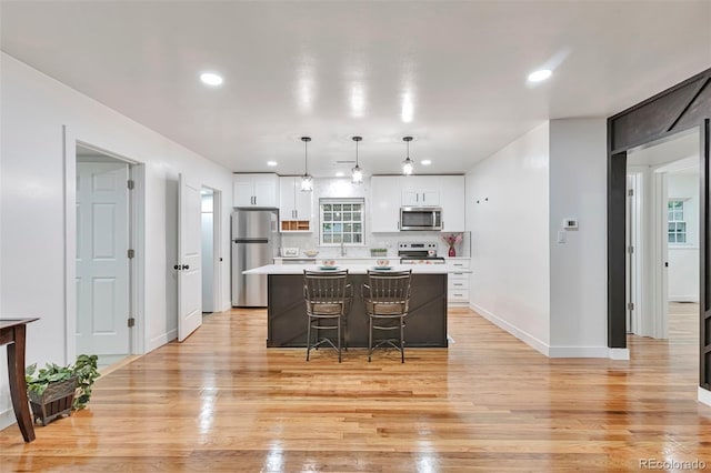 1325 Dayton St, Aurora, CO 80010 - kitchen featuring stainless steel appliances, white cabinets, a center island, light countertops, and light wood-type flooring