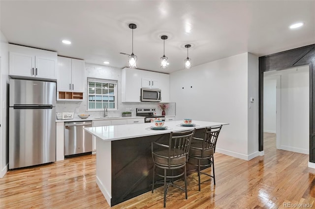 1325 Dayton St, Aurora, CO 80010 - kitchen with stainless steel appliances, light countertops, white cabinetry, light wood-type flooring, and recessed lighting