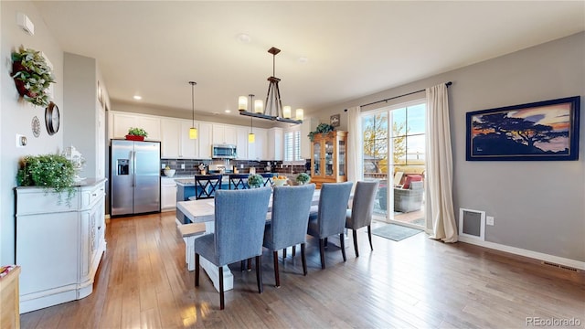 dining area with an inviting chandelier and light wood-type flooring