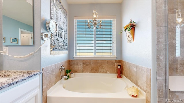 bathroom featuring an inviting chandelier, vanity, a wealth of natural light, and a bathtub