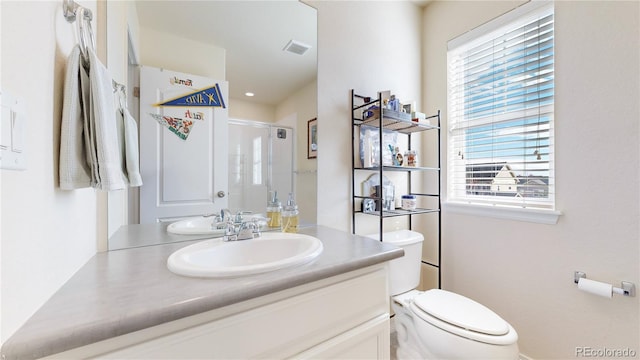 bathroom featuring vanity, plenty of natural light, a shower with door, and toilet