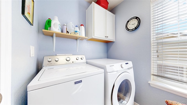 clothes washing area with cabinets and separate washer and dryer