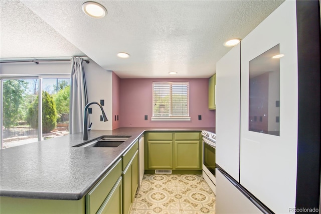 kitchen featuring stainless steel range with electric cooktop, a sink, a textured ceiling, visible vents, and green cabinets