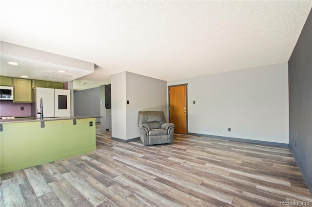 unfurnished living room featuring recessed lighting, baseboards, light wood finished floors, and a textured ceiling