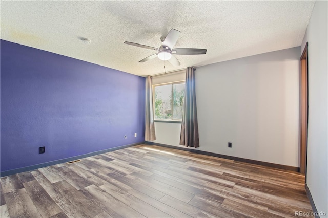 empty room with baseboards, a ceiling fan, a textured ceiling, and wood finished floors