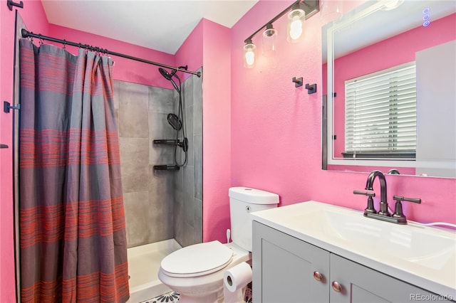 bathroom featuring toilet, a textured wall, tiled shower, and vanity