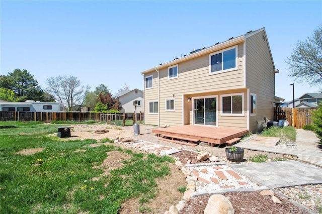 rear view of house featuring a fenced backyard, a wooden deck, and a lawn