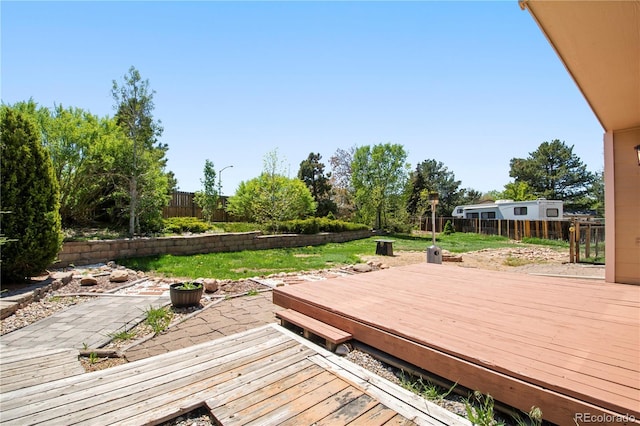 wooden terrace featuring a lawn, a fenced backyard, and a patio area