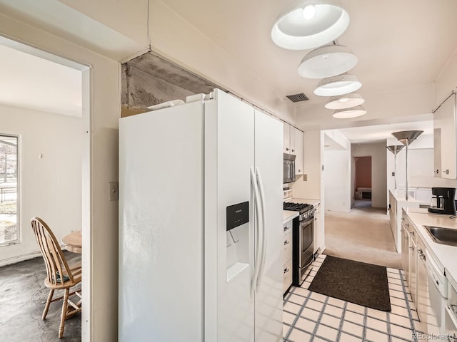 kitchen featuring white cabinets, appliances with stainless steel finishes, pendant lighting, and sink