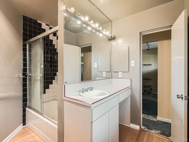 bathroom featuring hardwood / wood-style flooring, vanity, and shower / bath combination with glass door