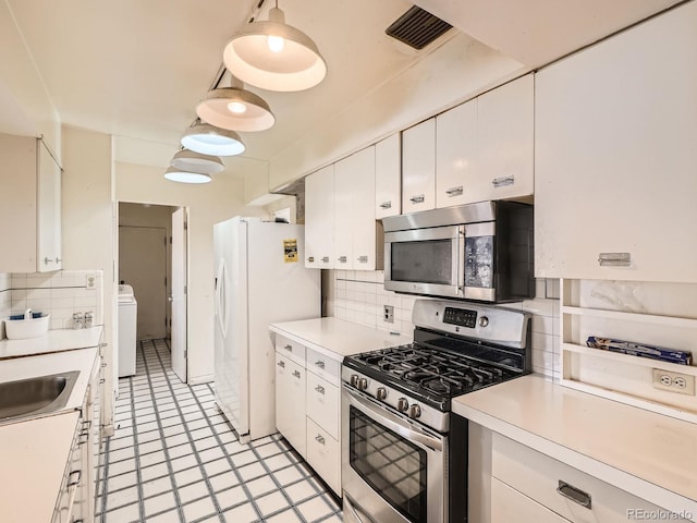 kitchen with appliances with stainless steel finishes, tasteful backsplash, white cabinetry, and pendant lighting