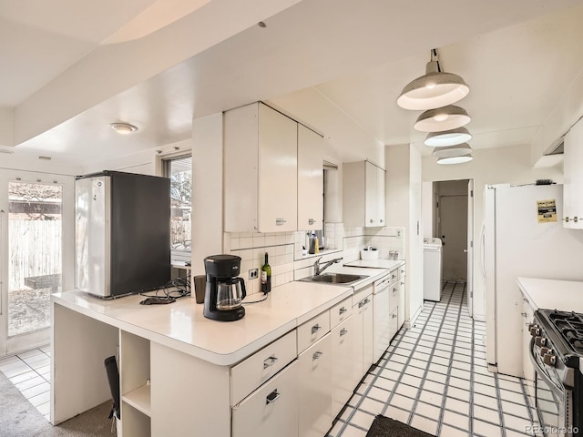 kitchen with sink, washer / dryer, white cabinetry, and backsplash