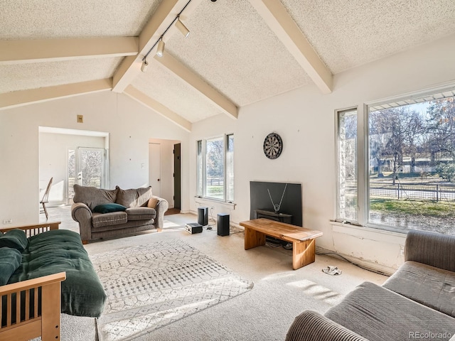 carpeted living room featuring vaulted ceiling with beams and a textured ceiling