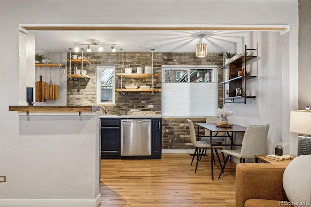 bar featuring hanging light fixtures, brick wall, stainless steel dishwasher, and light wood-type flooring