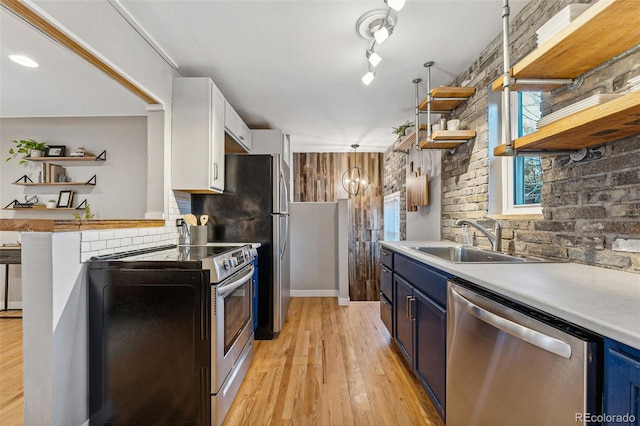 kitchen with white cabinetry, sink, stainless steel appliances, blue cabinets, and light hardwood / wood-style floors