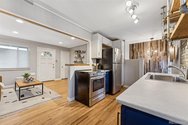 kitchen with light wood-type flooring, stainless steel appliances, sink, an inviting chandelier, and white cabinets