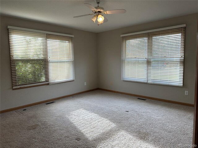 carpeted empty room with a wealth of natural light and ceiling fan