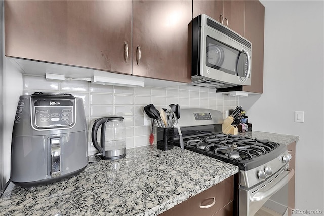 2229 Blake St Unit 505, Denver, CO 80205 - kitchen featuring appliances with stainless steel finishes, backsplash, and light stone counters