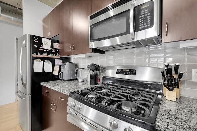 2229 Blake St Unit 505, Denver, CO 80205 - kitchen with stainless steel appliances, backsplash, light stone countertops, and dark brown cabinetry