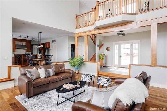 living room with a towering ceiling, rail lighting, and hardwood / wood-style floors