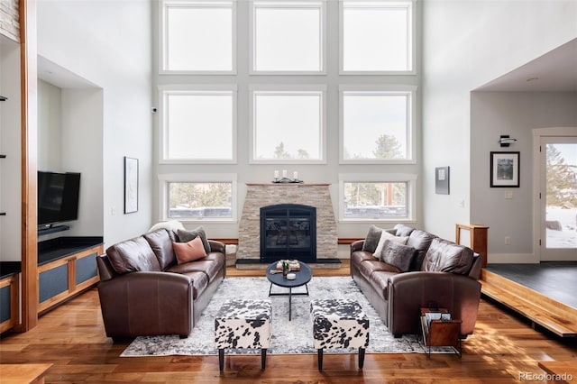 living room featuring a high ceiling, hardwood / wood-style floors, and a fireplace