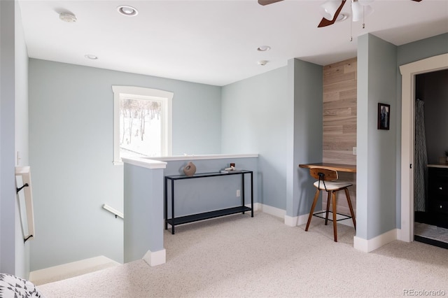 bedroom featuring ceiling fan, light colored carpet, and wooden walls