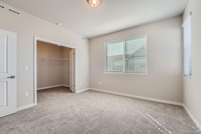 unfurnished bedroom featuring a spacious closet, light carpet, and a closet