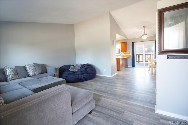 living room featuring ceiling fan, vaulted ceiling, and wood-type flooring