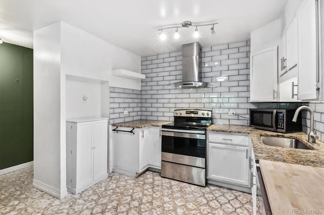 kitchen featuring wood counters, backsplash, stainless steel appliances, wall chimney range hood, and white cabinets