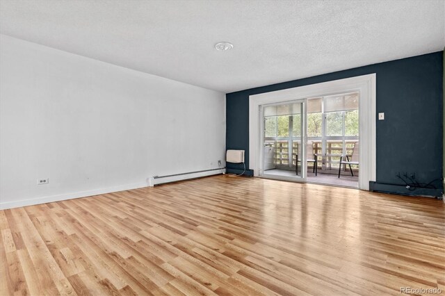 empty room with light wood-type flooring, a baseboard radiator, and a textured ceiling