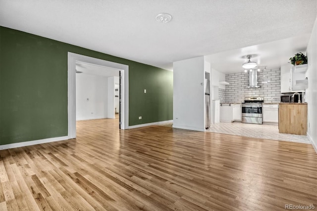 unfurnished living room with a textured ceiling and light hardwood / wood-style flooring