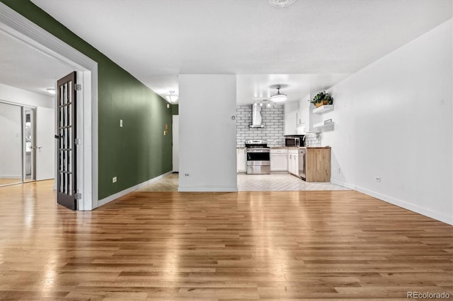 unfurnished living room with a textured ceiling and light hardwood / wood-style floors