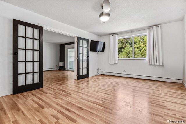 empty room featuring a baseboard radiator, light hardwood / wood-style floors, and a textured ceiling