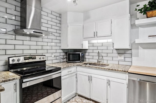 kitchen with open shelves, appliances with stainless steel finishes, a sink, wall chimney exhaust hood, and white cabinetry
