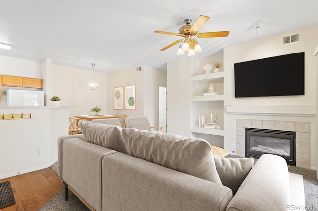 10784 W 63rd Pl Unit 205, Arvada, CO 80004 - living area with built in shelves, wood finished floors, a fireplace, a ceiling fan, and a chandelier