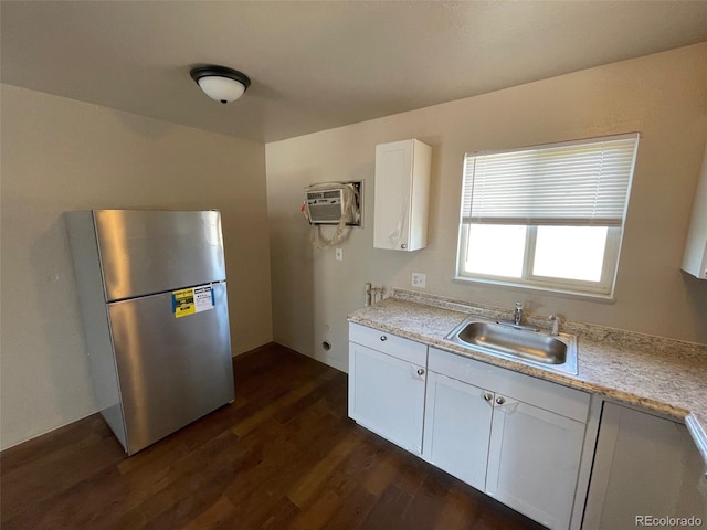 kitchen featuring stainless steel refrigerator, sink, dark hardwood / wood-style floors, a wall unit AC, and white cabinets