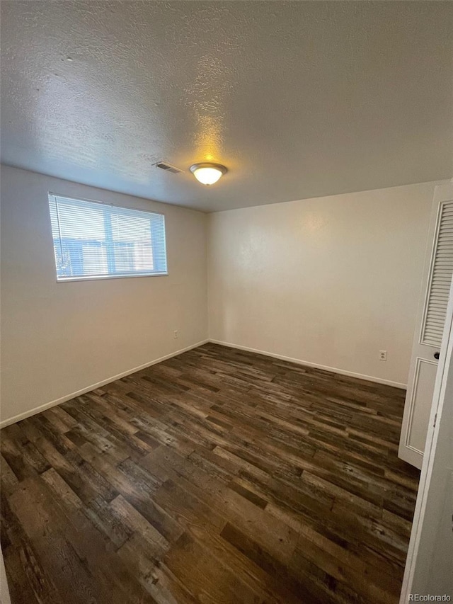 empty room featuring a textured ceiling and dark hardwood / wood-style flooring