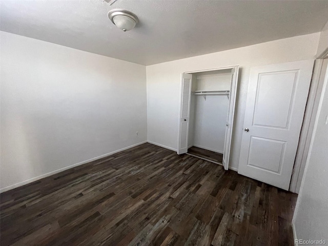 unfurnished bedroom with dark hardwood / wood-style flooring and a closet