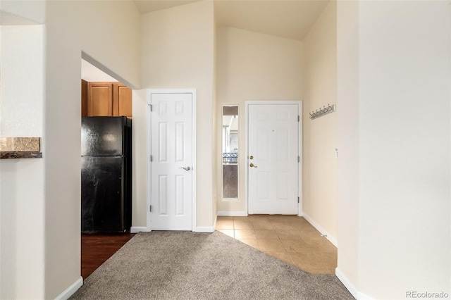 kitchen featuring black refrigerator, high vaulted ceiling, and tile patterned floors