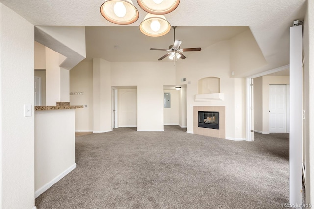 unfurnished living room featuring ceiling fan, high vaulted ceiling, electric panel, carpet floors, and a tiled fireplace