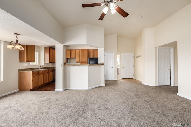 kitchen with carpet flooring, black fridge, ceiling fan with notable chandelier, high vaulted ceiling, and hanging light fixtures